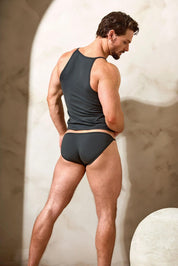 Man in fitted black tank top and bikini briefs, modeling men's underwear with athletic build
