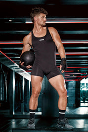 Athletic man in black singlet bodysuit holding medicine ball in gym, men's sporty underwear