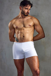 Muscular man modeling tight white men's boxer briefs against a gray studio background.