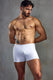 Muscular man modeling tight white men's boxer briefs against a gray studio background.