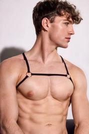 Fit man wearing black minimalist harness, showing muscular torso, trendy men's fashion