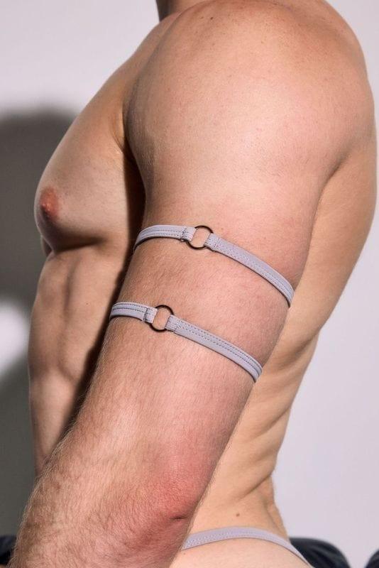 Male model in minimal grey harness arm straps, showing athletic physique.