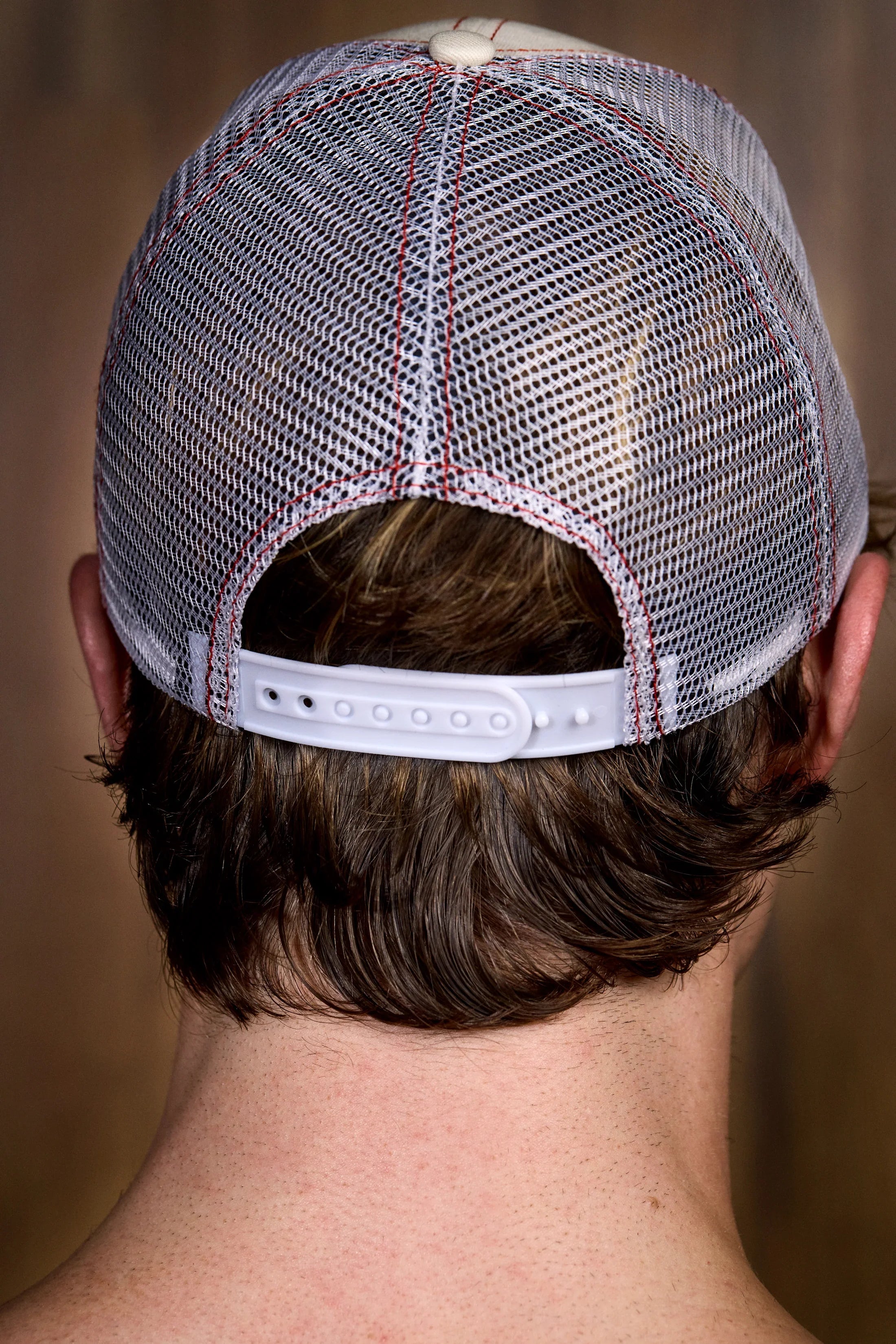 Close-up of a man's head wearing a white mesh trucker cap with adjustable strap