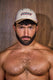 Shirtless man with beard wearing mesh trucker hat with COYOTE logo, wood background