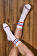 White athletic socks with red and blue stripes worn on crossed legs on wood floor