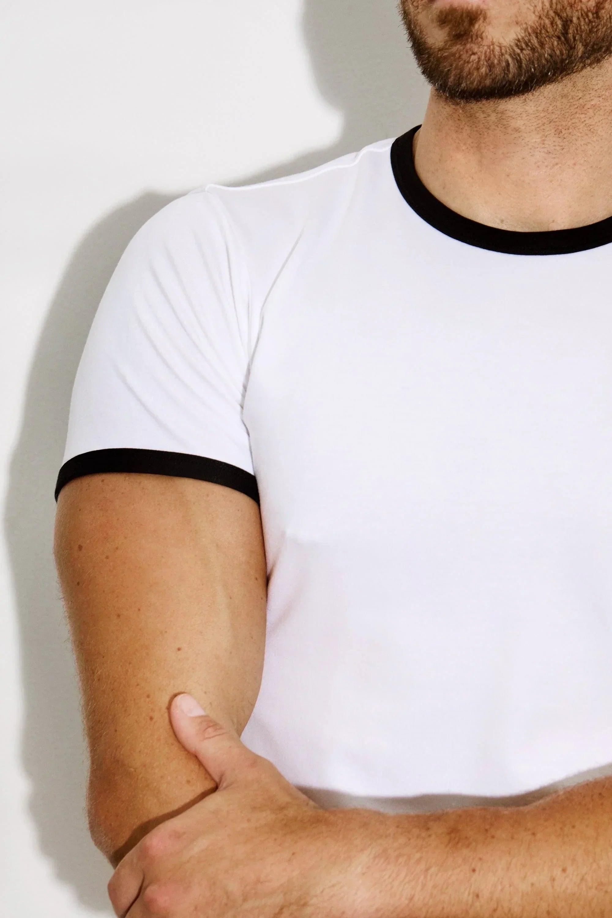 Close-up of a man wearing a fitted white ringer T-shirt with black trim on sleeves and collar