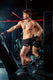 Athletic man in black sports shorts and gloves training with punching bag in gym