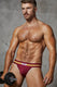 Muscular man in maroon athletic underwear holding a dumbbell, posing against grey background