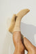 Man's legs crossed wearing beige socks against a light wall, men's fashion socks