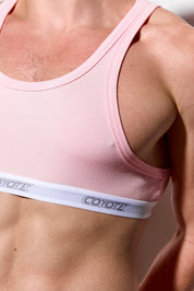 Close-up of a person wearing a pink ribbed sports bra with Coyote logo waistband