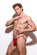 Shirtless male model wearing red men's thong underwear against white background