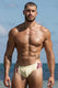 Muscular man in cream swim briefs with burgundy stripes, beach backdrop, showcasing men's swimwear