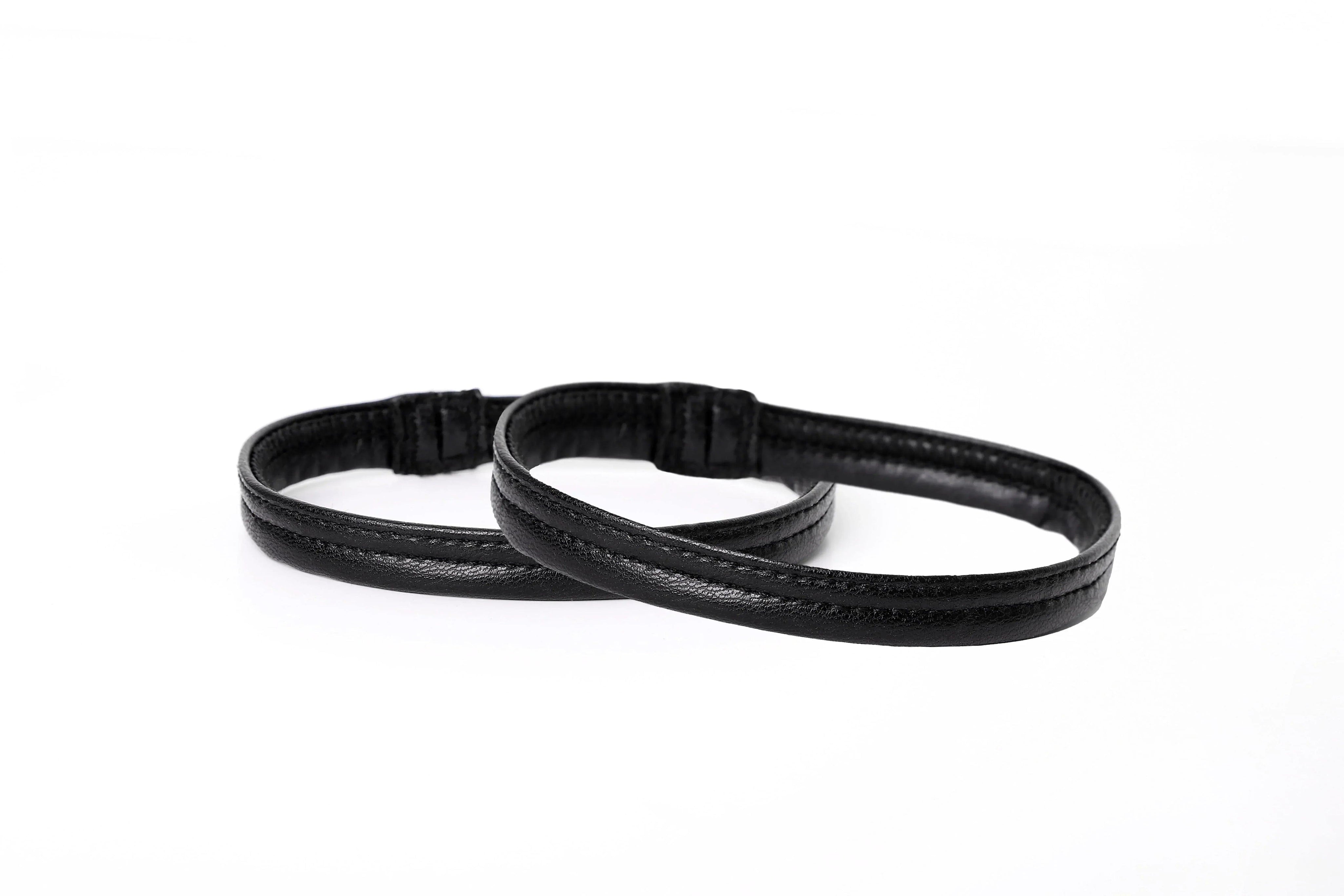 Two black leather armbands with a sleek, stitched design on a white background