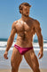Muscular man in magenta swim briefs posing on sunny beach with blue sky and waves