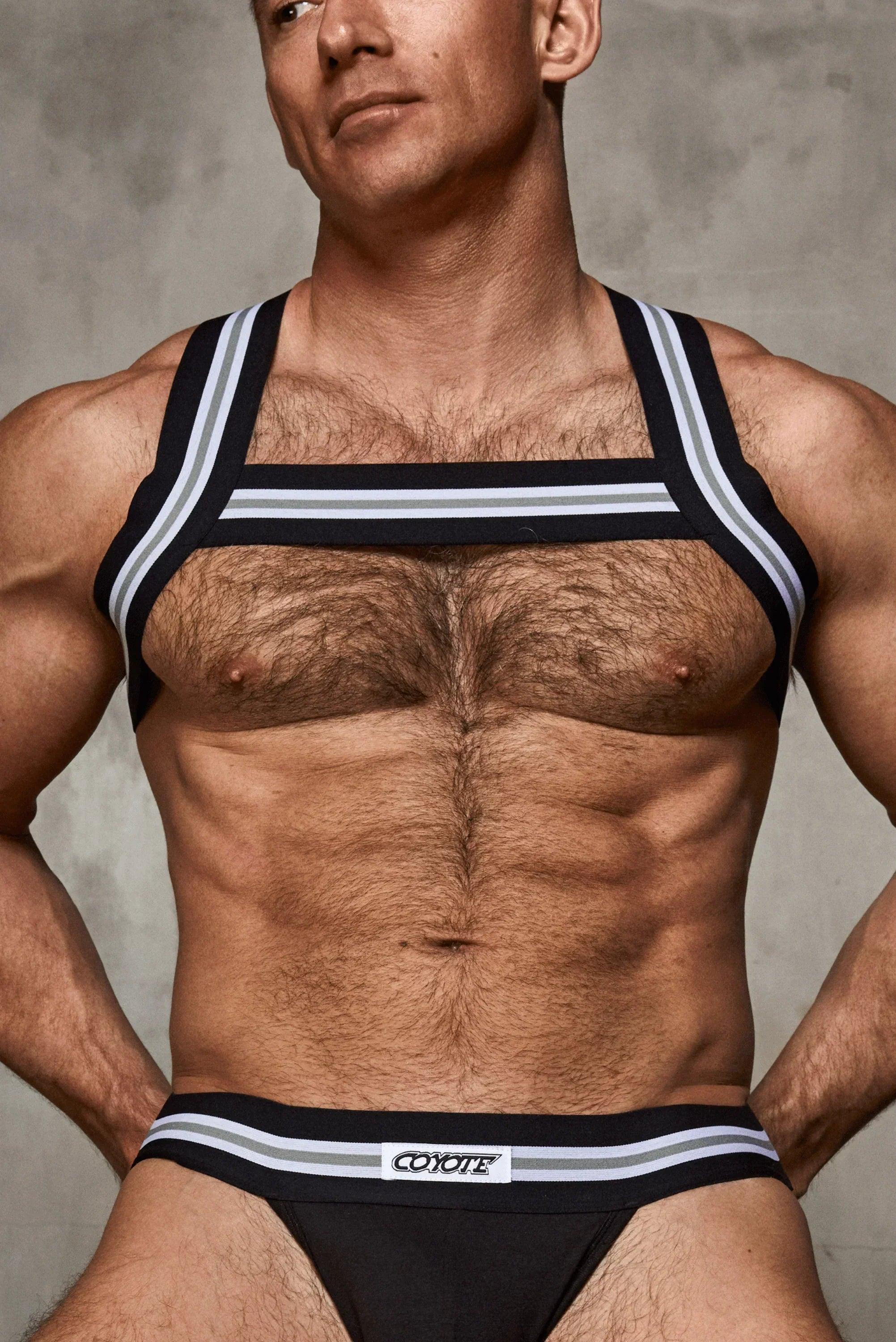Muscular man modeling black harness and jockstrap underwear with striped waistband