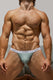 Muscular man modeling mint green men's bikini underwear with white waistband, sitting indoors
