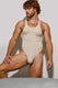 Athletic man in beige men's singlet bodysuit posing against plain background
