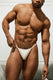 Athletic man modeling white ribbed men’s thong underwear, posing in indoor setting